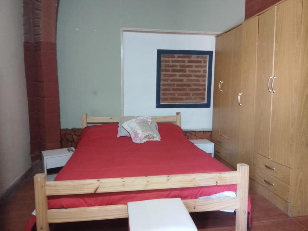 a bedroom with a wooden bed with a red blanket at Los Patos in Chumillo