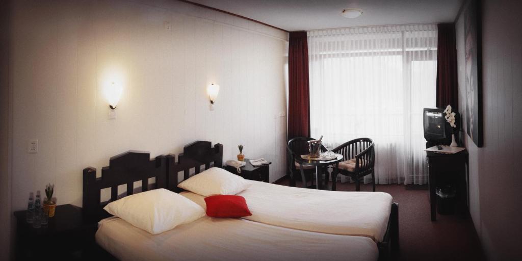 デン・ヘルダーにあるHotel Den Helderのベッドルーム1室(白いシーツと赤い枕のベッド1台付)