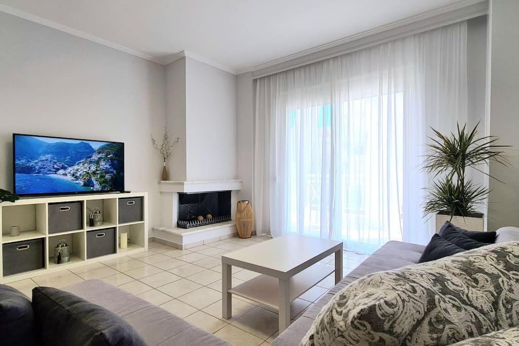 a living room with a couch and a tv at Ivanna apartment in Nea Moudania