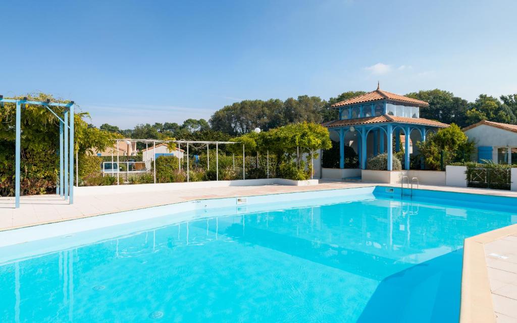 a swimming pool with a gazebo in the background at Lagrange Vacances Le Clos des Chênes in Les Mathes