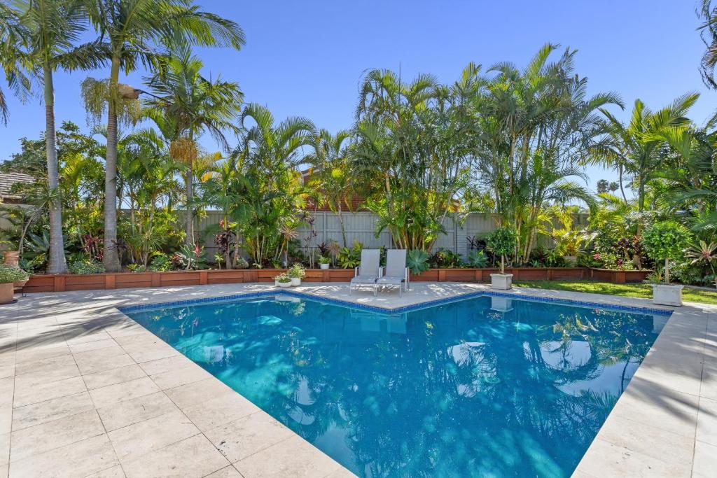 a swimming pool with palm trees in the background at Lillypilly Bed and Breakfast in Mooloolaba