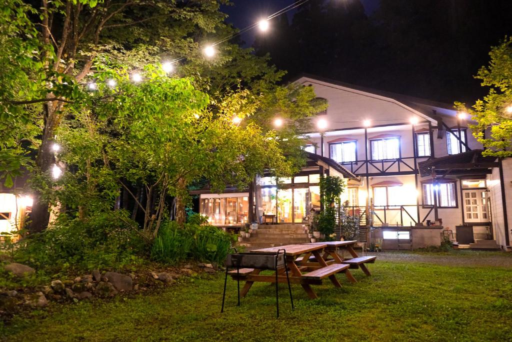 a picnic table in front of a house at night at Kizuna Lodge & BBQ Centre in Hakuba