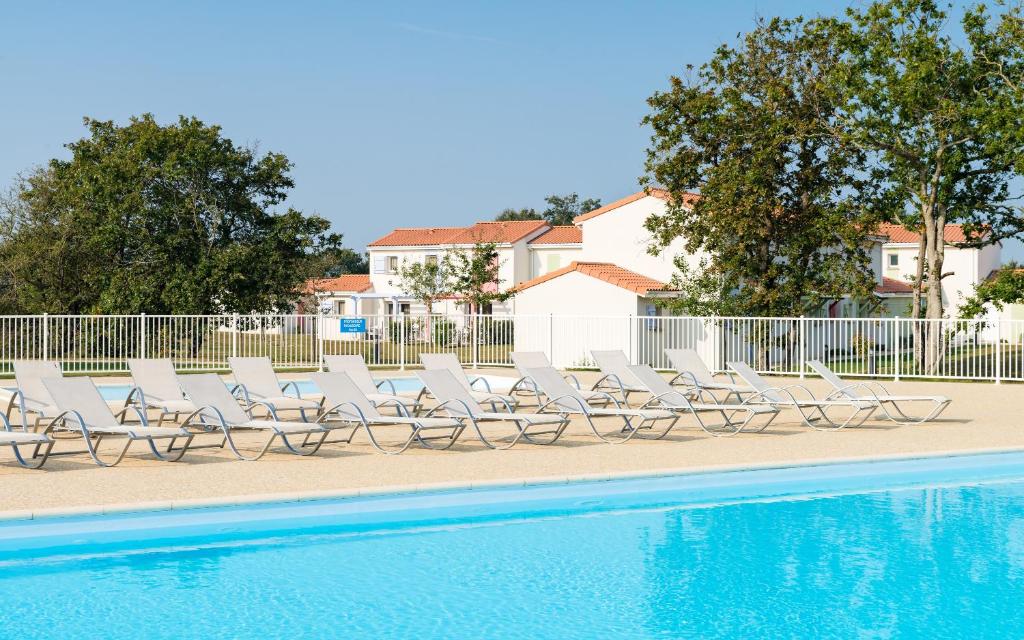 - une rangée de chaises longues à côté de la piscine dans l'établissement Lagrange Vacances Le Village de la Mer, à Talmont-Saint-Hilaire