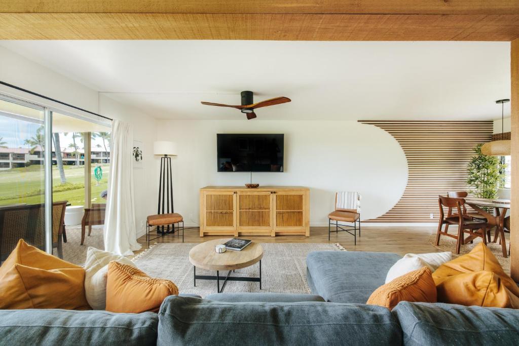 ein Wohnzimmer mit einem blauen Sofa und einem TV in der Unterkunft The Olena at Keauhou Bay in Kailua-Kona