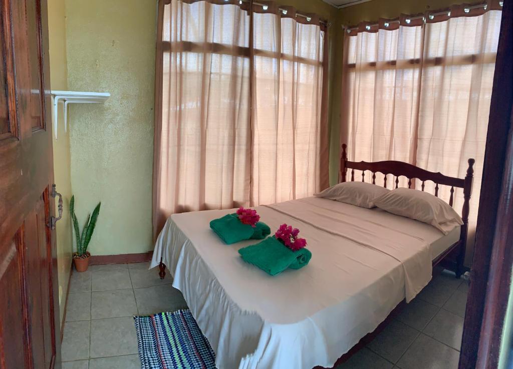 een slaapkamer met een bed met 2 bloemen erop bij Blue House in Puerto Jiménez