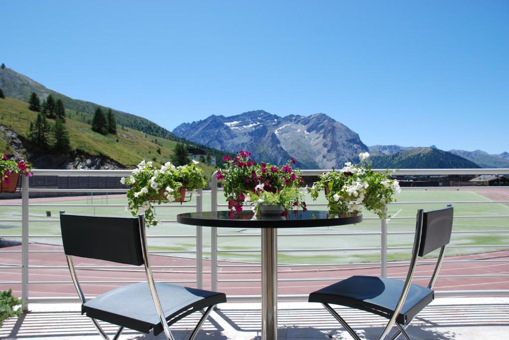 two chairs and a table with flowers on a patio at Hotel Lago Losetta in Sestriere
