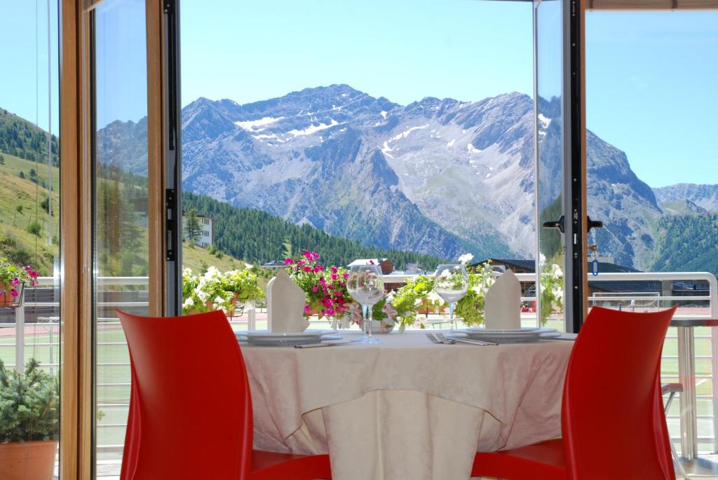 a table with red chairs and a view of mountains at Hotel Lago Losetta in Sestriere