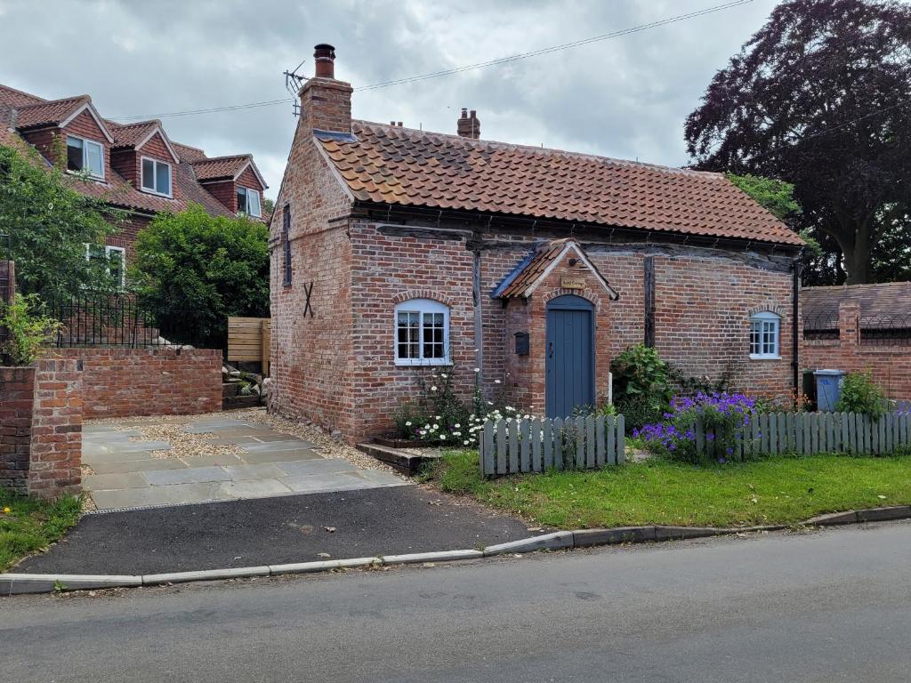 a brick house with a blue door in a yard at Auld Cottage in Norwell