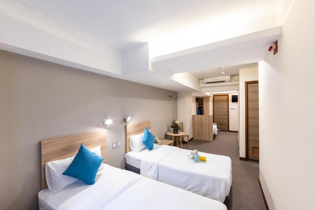 a hotel room with two beds with blue pillows at metacity living in Hong Kong
