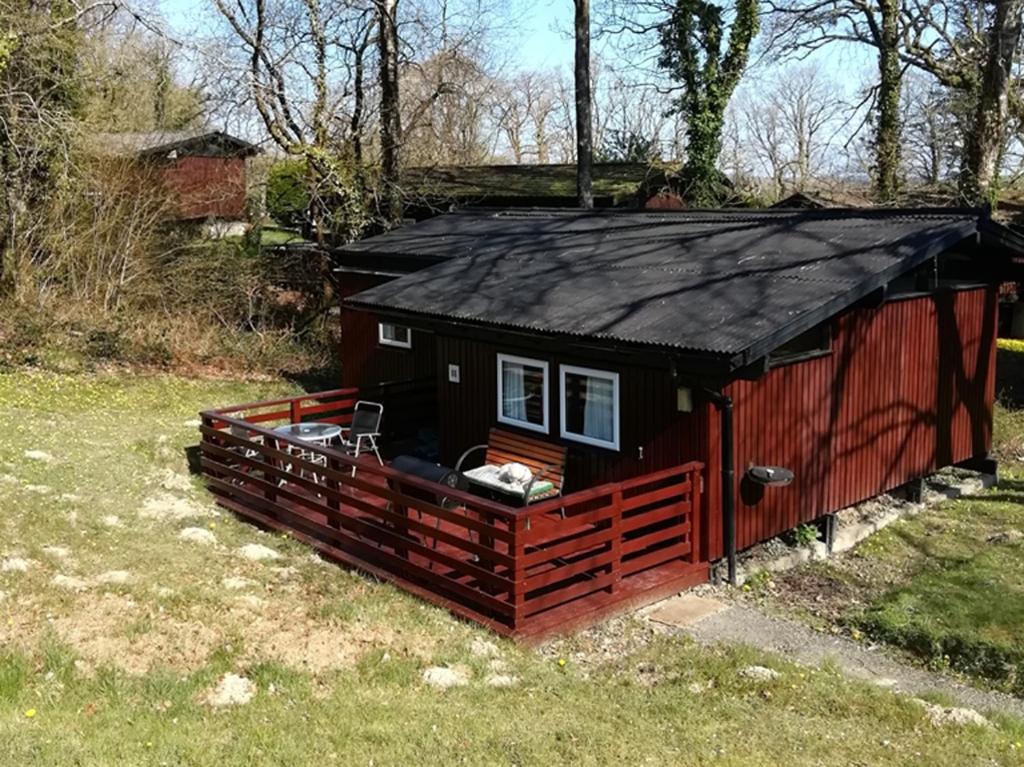 a small red house with a black roof at Nuthatch Lodge is set in 24 acres of woodparkland near the village of Cenarth in Newcastle Emlyn