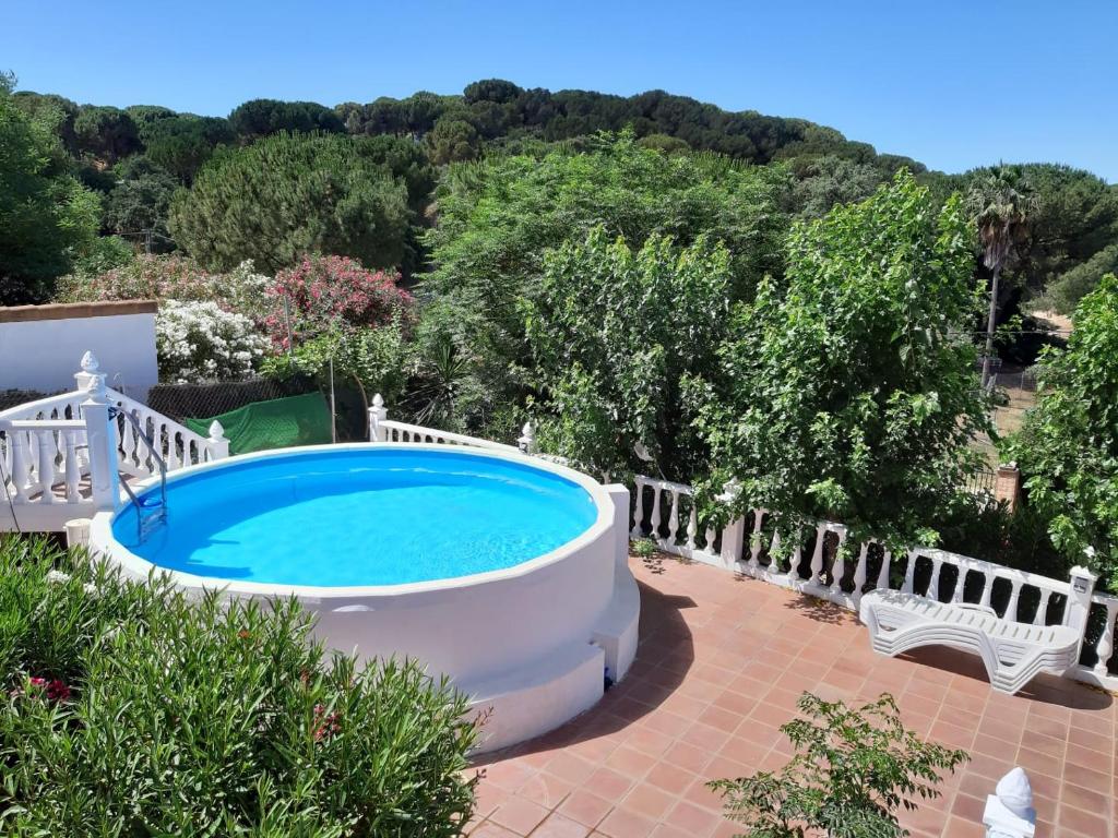 una piscina in un cortile con una recinzione bianca e una panchina bianca di Chalet rural La Solana, a 12 Kilómetros de Córdoba en plena sierra, con piscina a Cordoba