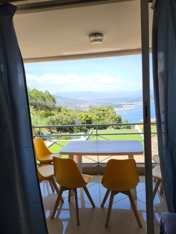 - une vue depuis le balcon d'une maison avec une table et des chaises dans l'établissement VUE MER ET ESTEREL SUR LA BAIE DE CANNES, à Théoule-sur-Mer