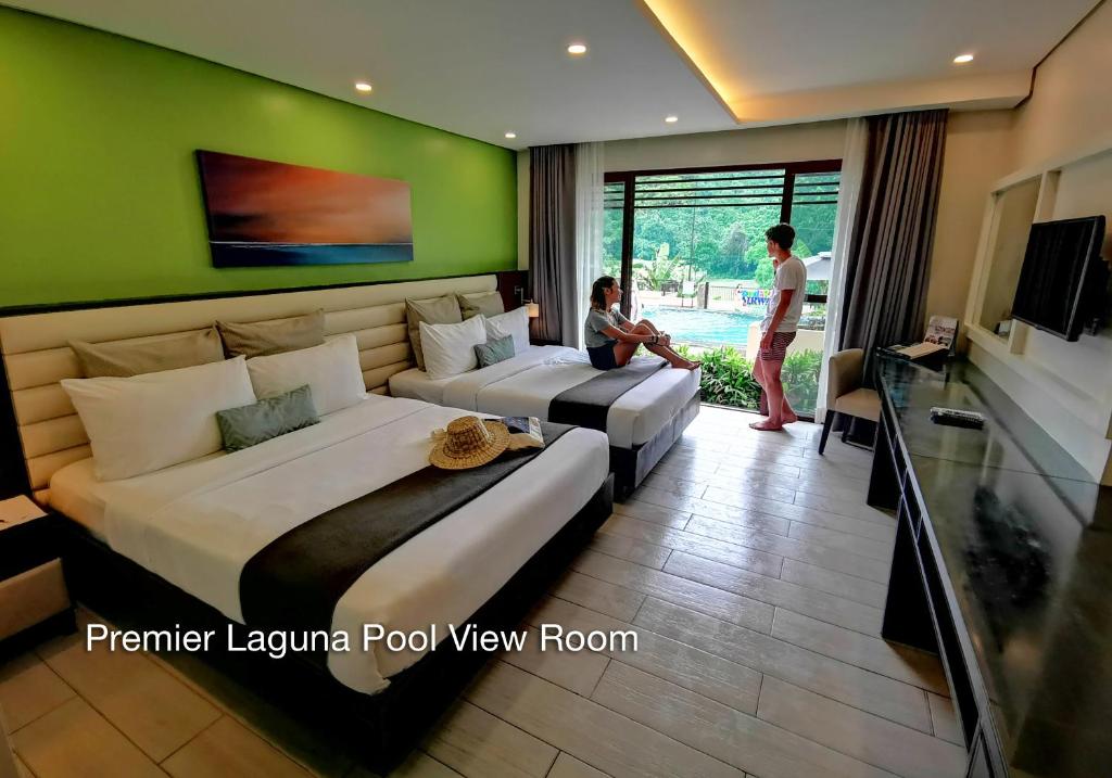 two beds in a hotel room with a person sitting on the bed at Fairways and Bluewater Boracay in Boracay