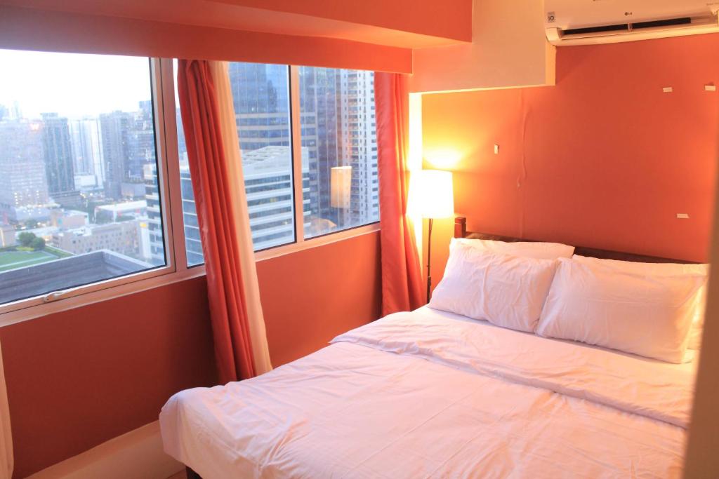 a bedroom with a bed and a large window at A2J BGC Luxury 2BR Loft Near Burgos Circle, Malls in Manila