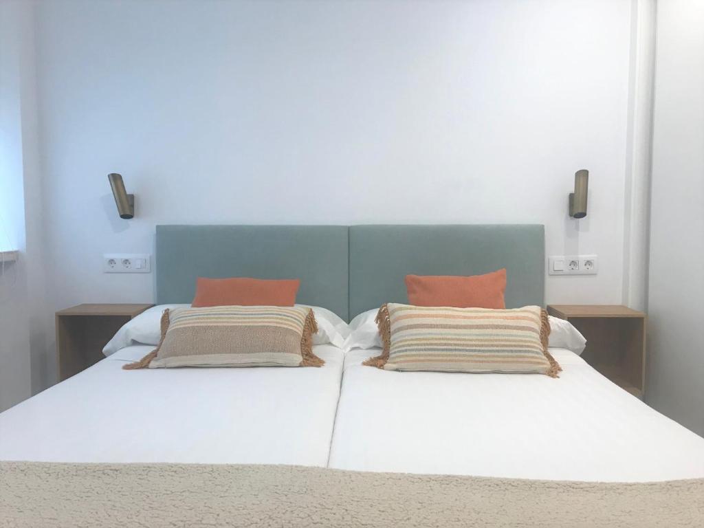 una camera con un letto bianco con due cuscini di Apartamentos Puerto Norte - Apto 3 a Puerto de Vega