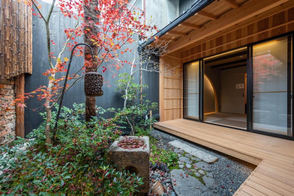 einen Garten vor einem Gebäude mit einer Holzveranda in der Unterkunft TABITABI KANOE MITSU in Kyoto