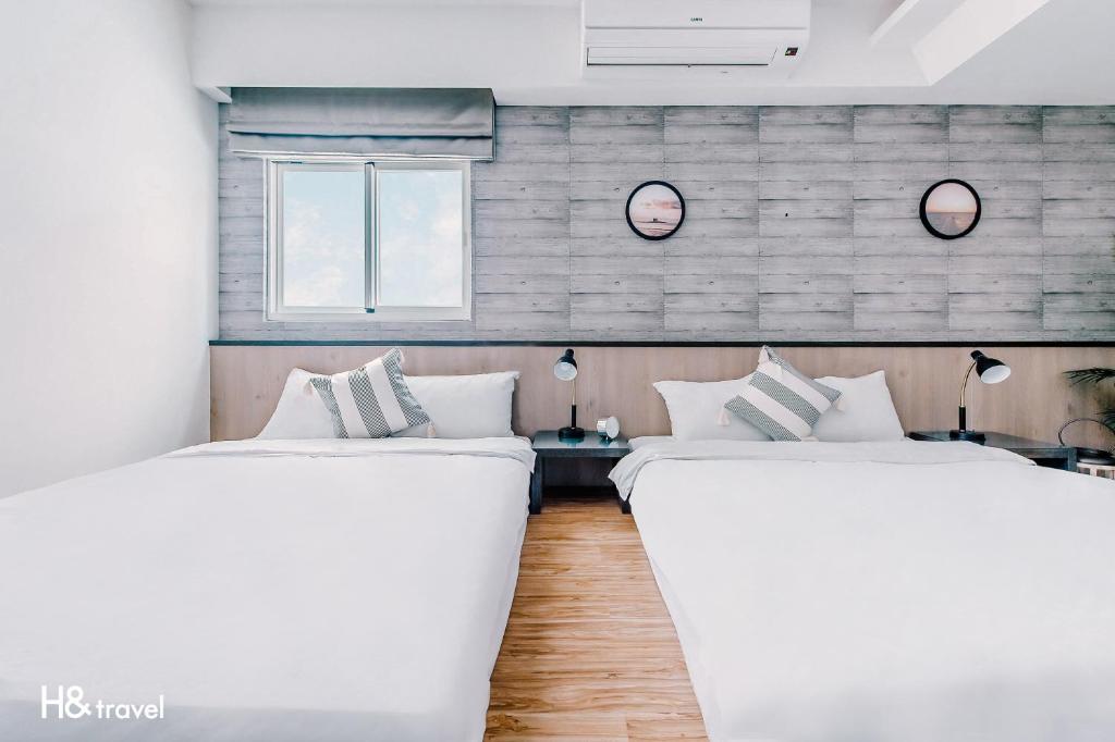 two white beds in a room with two windows at 澎湖臨海居會館 l 電梯 l 停車場 in Magong