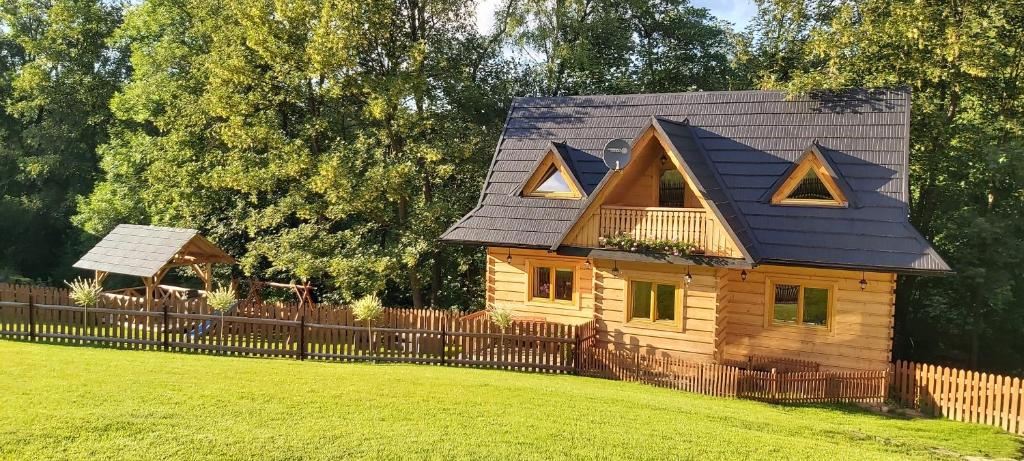 a wooden house with a black roof and a fence at Domek Pod Ubocom in Zakopane