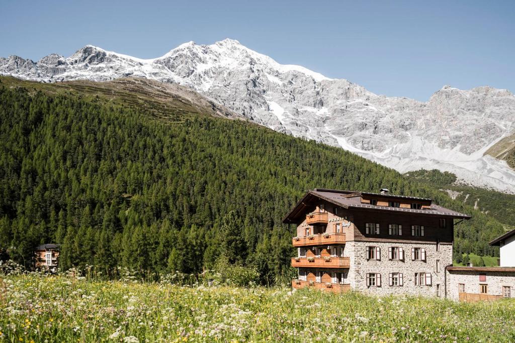 a building on a hill with mountains in the background at Pension Dangl - Glacier Rock in Solda