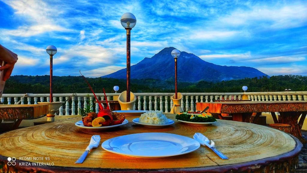 a table with plates of food on a balcony with a mountain at Baletin Hometel in Basco
