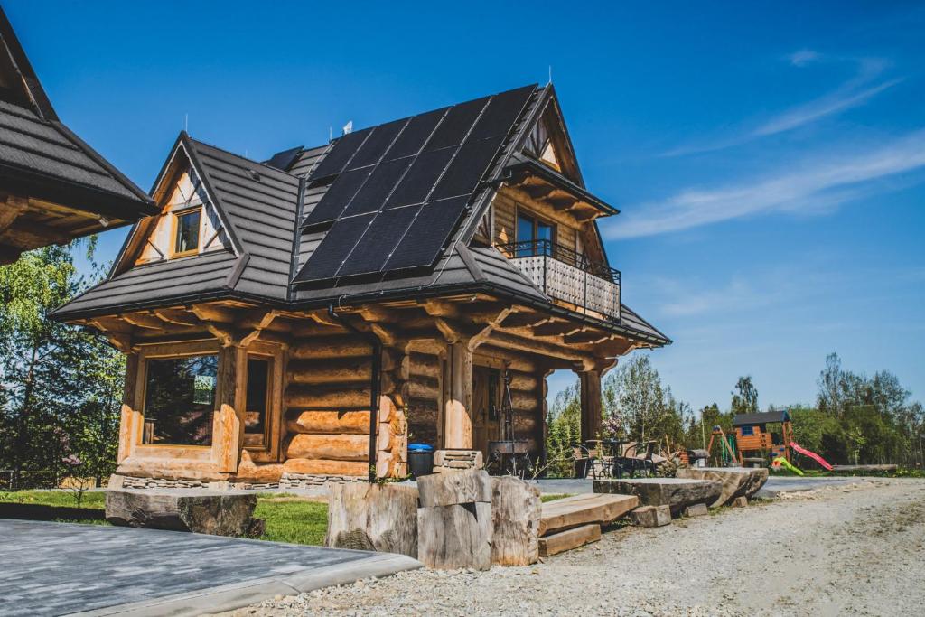 a log cabin with solar panels on its roof at Domki i Apartamenty Na Wyskówkach Jacuzzi & Sauna in Zakopane