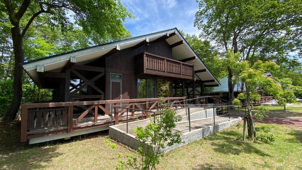 a house with a large deck in a park at Tabinoteitaku Yakurai Cottage in Osaki