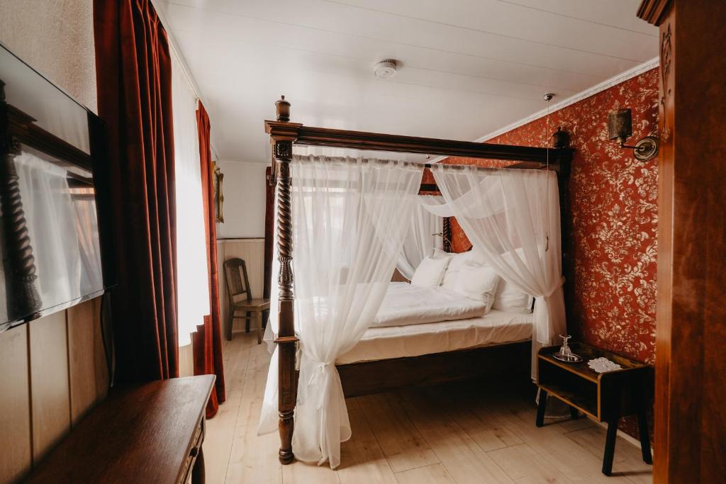 um quarto com uma cama de dossel e cortinas brancas em Altes Häusle am Waschbach-Weinberg em Edenkoben