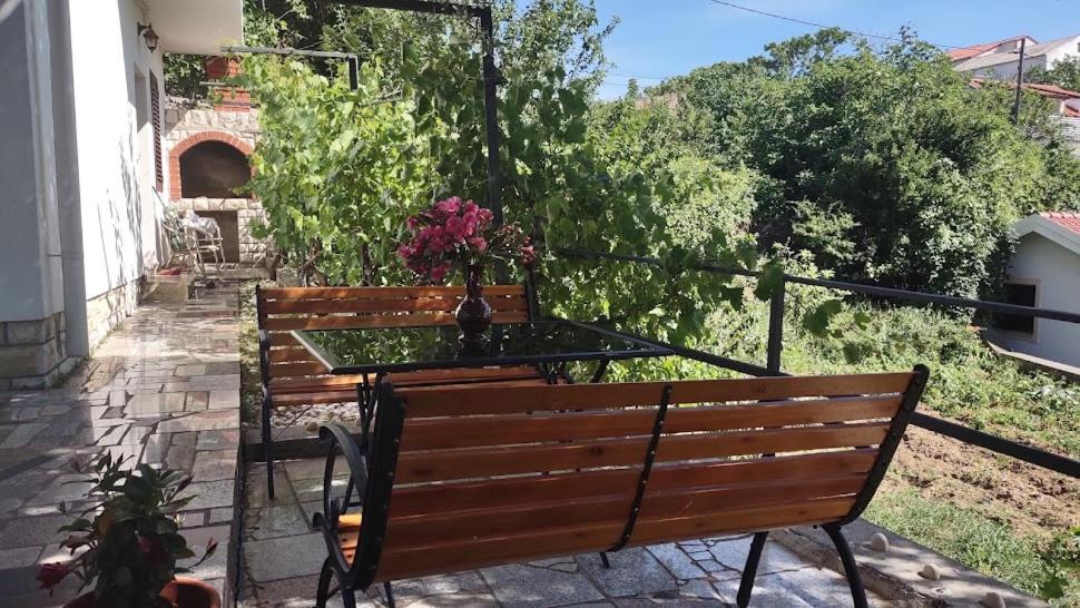 a wooden bench with a table and flowers on it at House Branka in Kampor