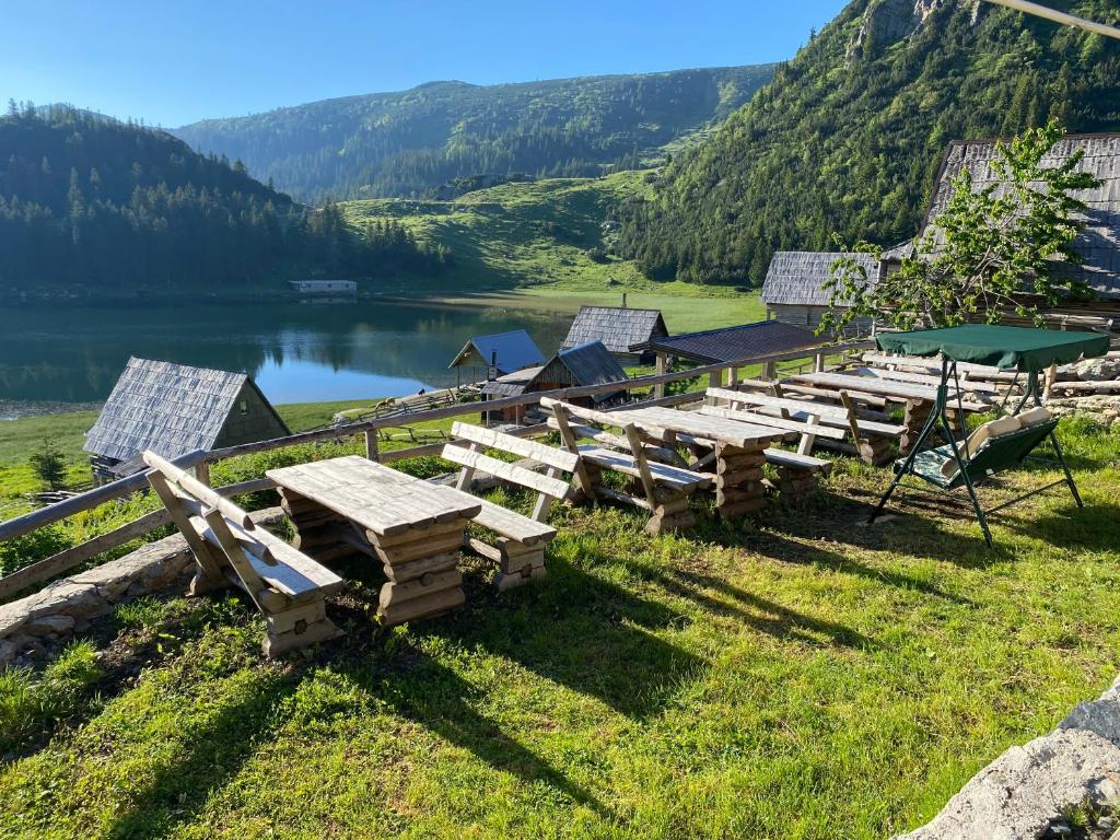 a group of picnic tables on the grass near a lake at Zlatna koliba Namir Zuka in Fojnica
