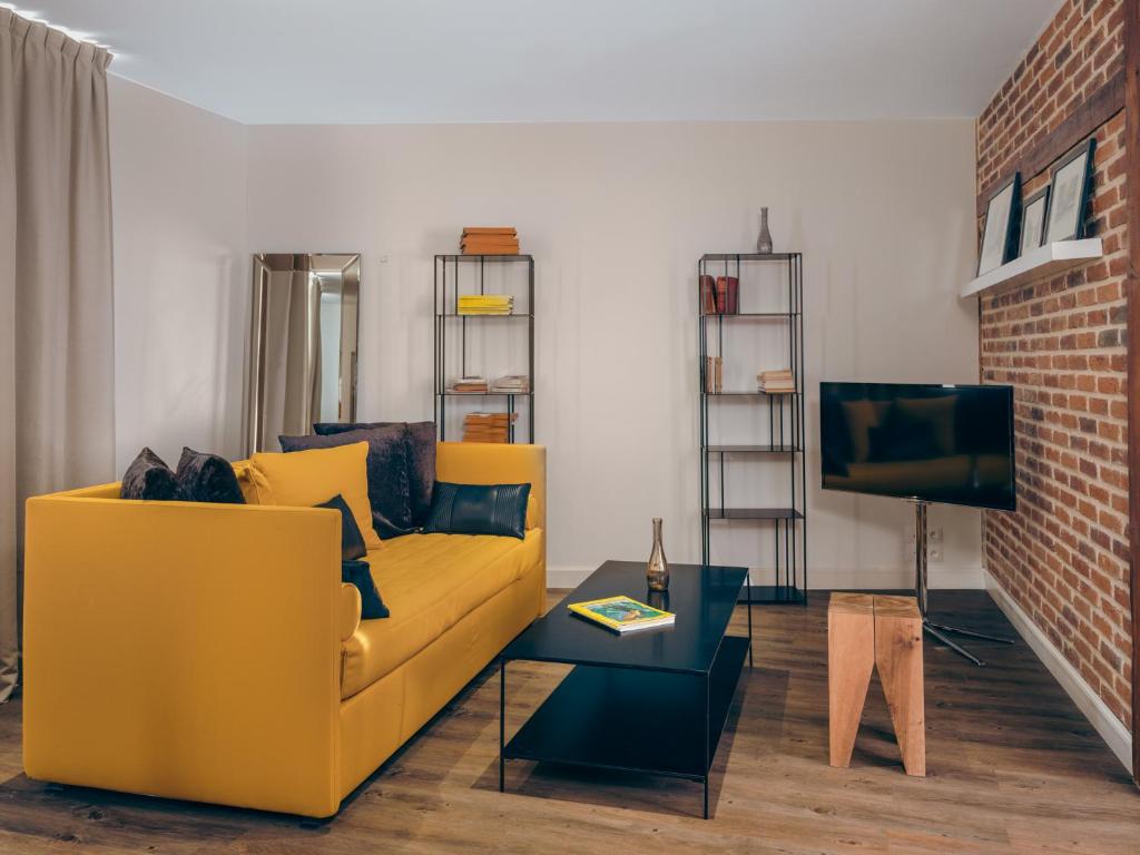 - un salon avec un canapé jaune et une télévision dans l'établissement Le Nemours - Appartements Parcheminerie, à Rennes