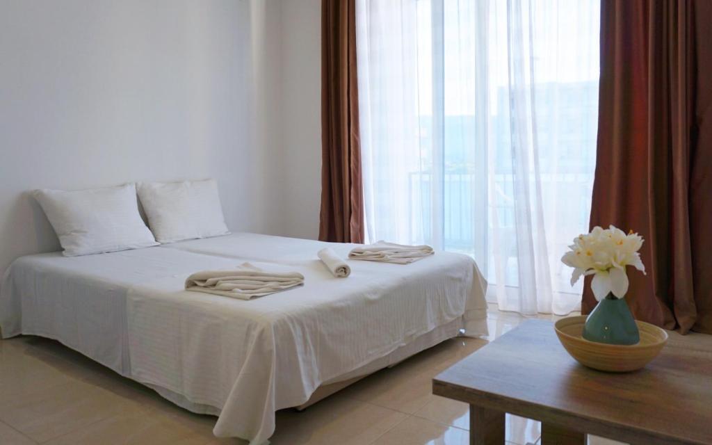 a bedroom with a white bed with a table and a window at Ponte Apartments in Ulcinj