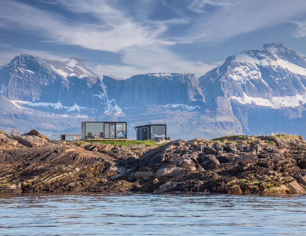 a house on a rocky island with mountains in the background at Cool cabins Sandhornøy in Lekanger