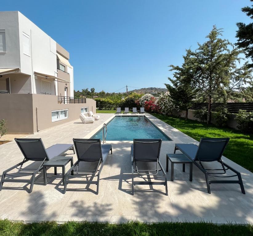 a group of chairs sitting next to a swimming pool at Villa Sweven, Luxury Living Chania in Souda