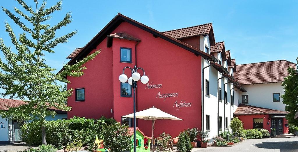 a red building with an umbrella in front of it at Hotel Bei den Tongruben in Ravolzhausen