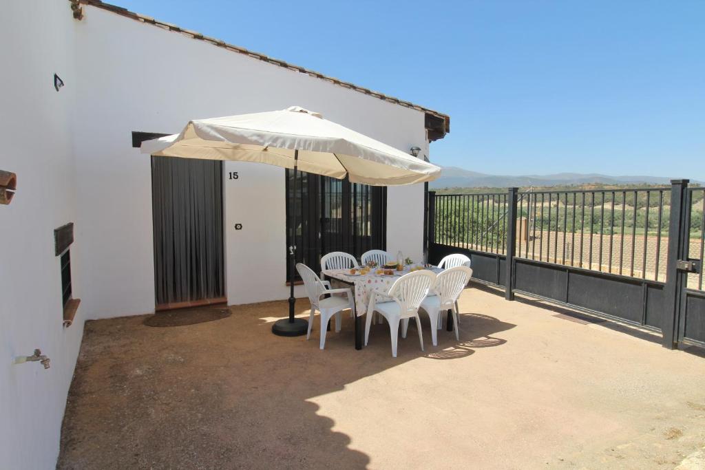 une terrasse avec une table, des chaises et un parasol dans l'établissement Casa Cueva Bella Vista, à Alcudia de Guadix