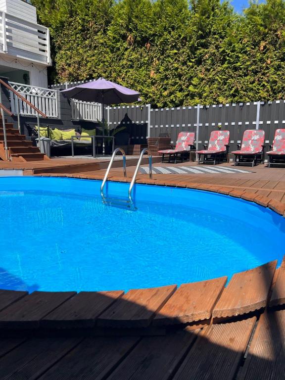 una piscina azul con sillas y sombrilla en O&W Ferienhaus mit Pool nähe Nürburgring, Adenau, en Adenau