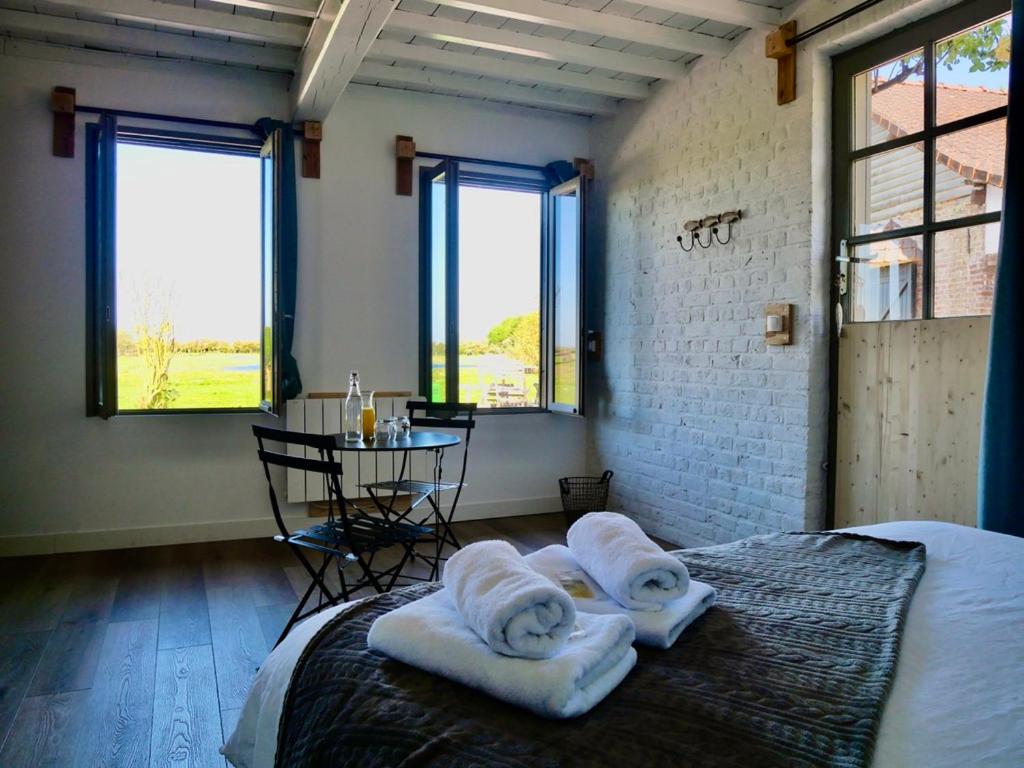 1 dormitorio con toallas en una cama con mesa en Chambres d'Hôtes et Gîte de La Vieille Ecluse en Quend