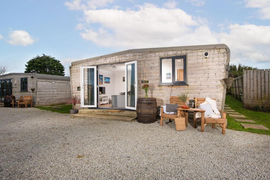 una pequeña casa de ladrillo con mesa y sillas en Wheal Jewel- Beautifully Fitted Wooden Lodge Helston Cornwall en Helston