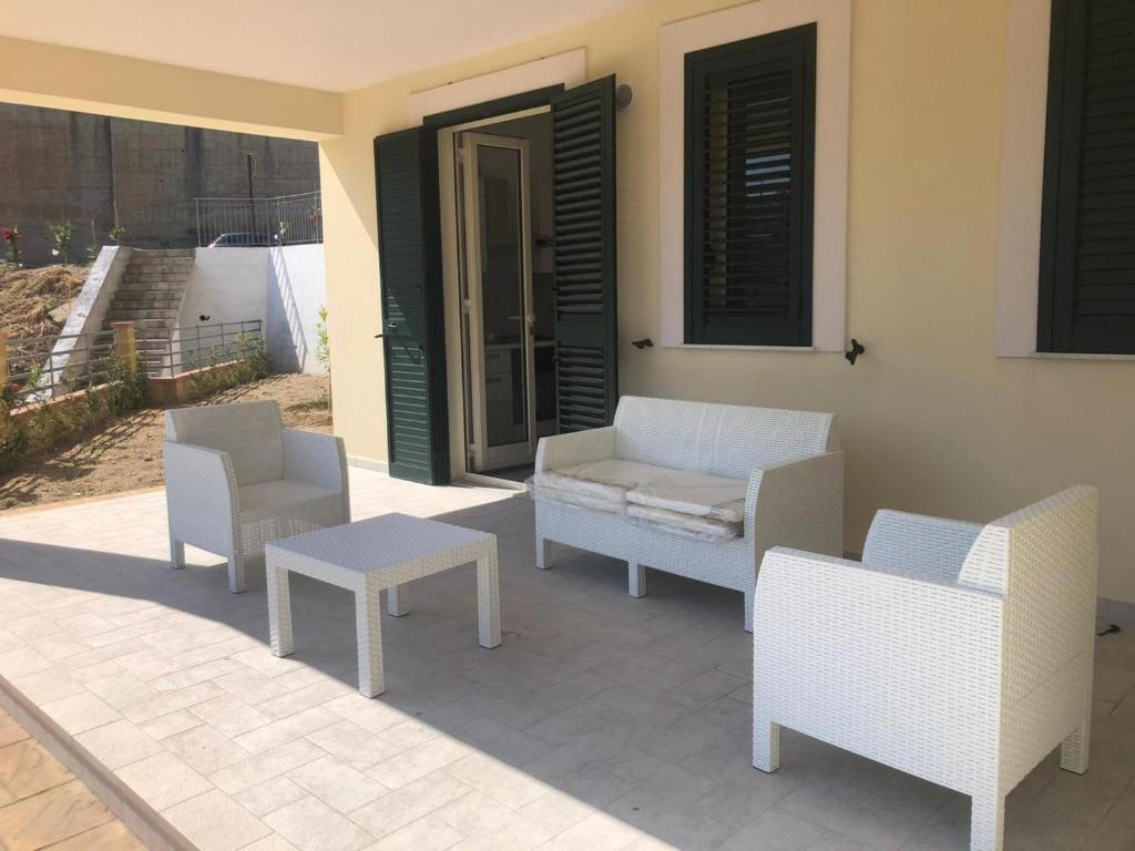 een patio met stoelen, een bank en een tafel bij Calanovella Mare piano terra 5 in Piraino
