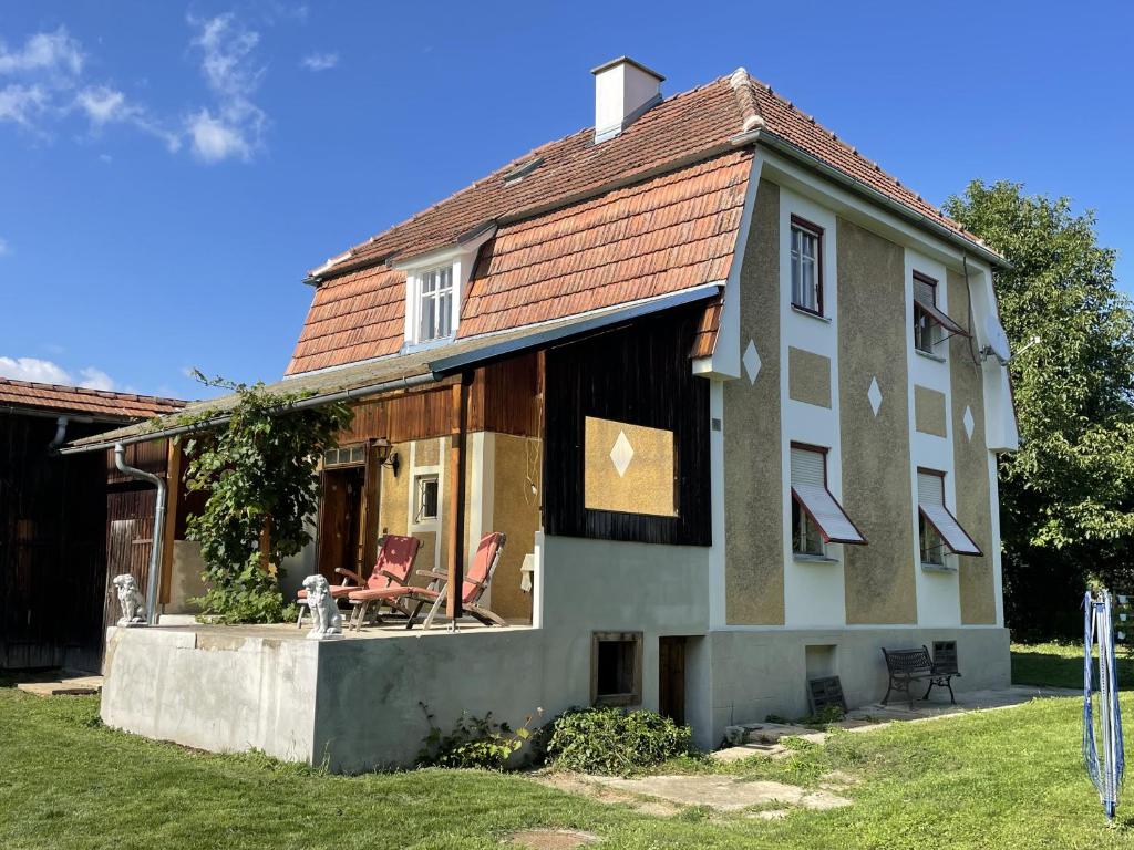 a house with two chairs on the front of it at Landhaus im Hartbergerland in Hartberg