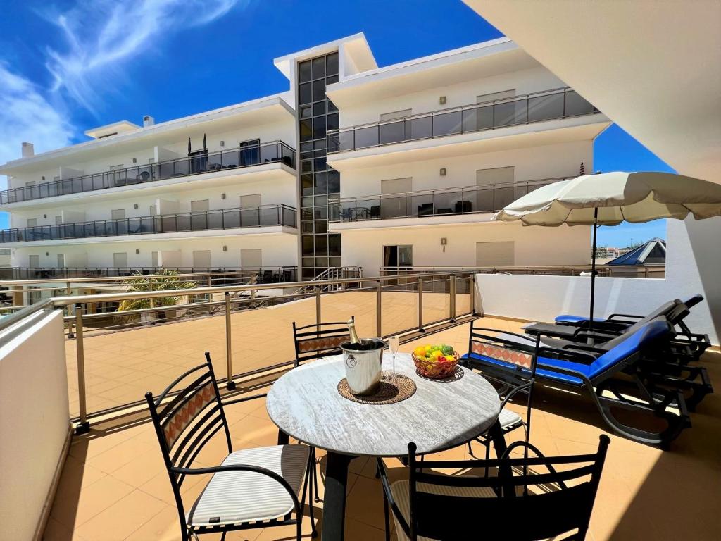 Un balcón con una mesa y sillas y un edificio. en Albufeira Terrace With Pool by Homing, en Albufeira