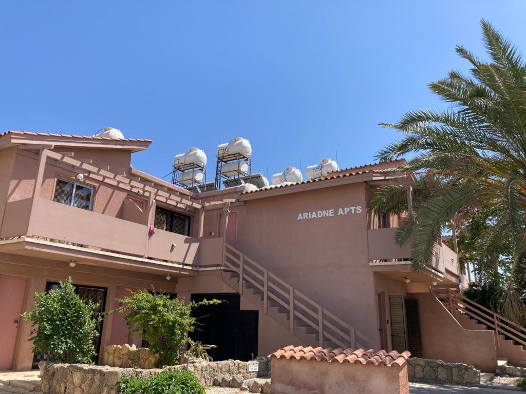 une grande maison rose avec un palmier dans l'établissement Ariadne Apartments, à Paphos