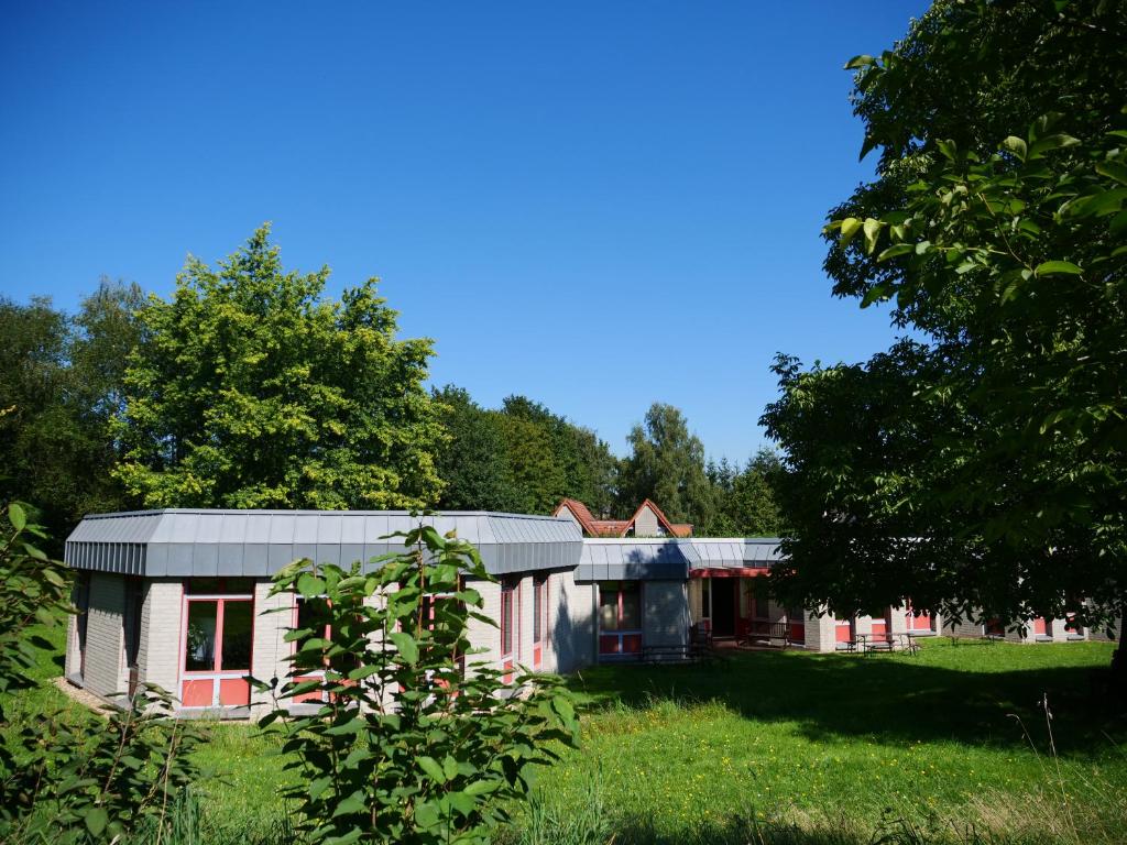 a house in the middle of a field with trees at Nell-Breuning-Hotel in Herzogenrath