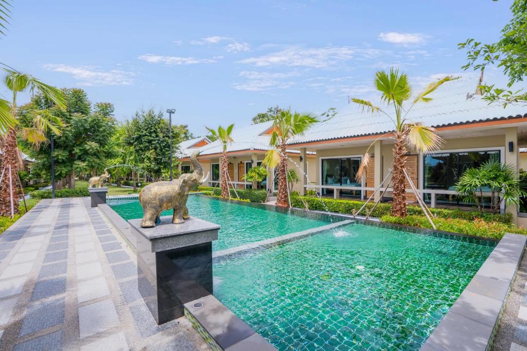 una piscina frente a una casa con una estatua de oso al lado en Tontan Resort Cha-am, en Cha Am