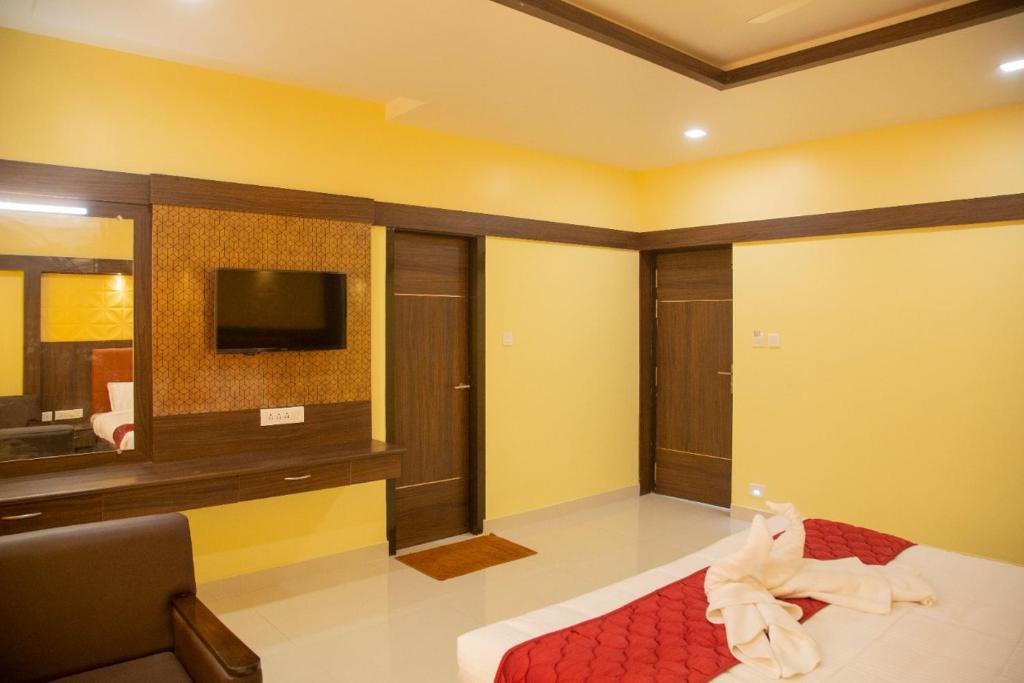 Habitación con cama, TV y sofá. en sri balaji grand hotel, en Kumbakonam