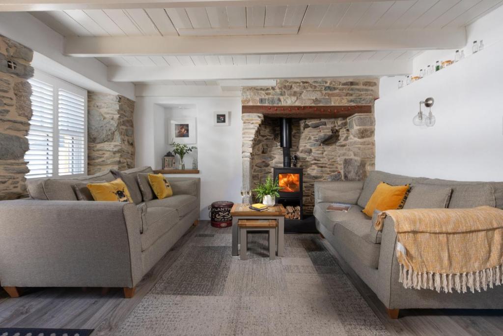 a living room with two couches and a fireplace at Eastleigh Cottage, Marazion in Marazion