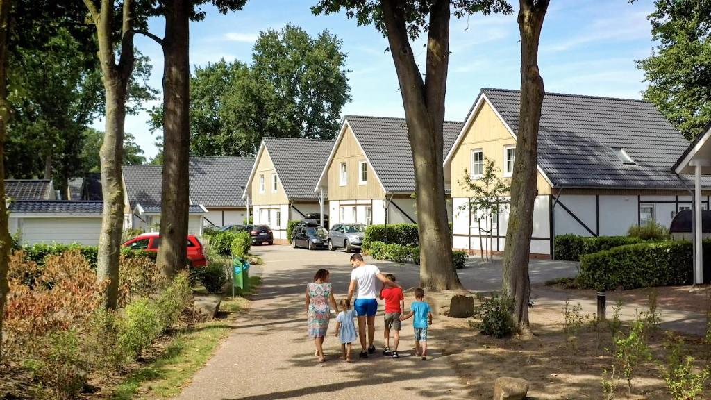 a group of children walking down a sidewalk in front of houses at EuroParcs Limburg in Susteren