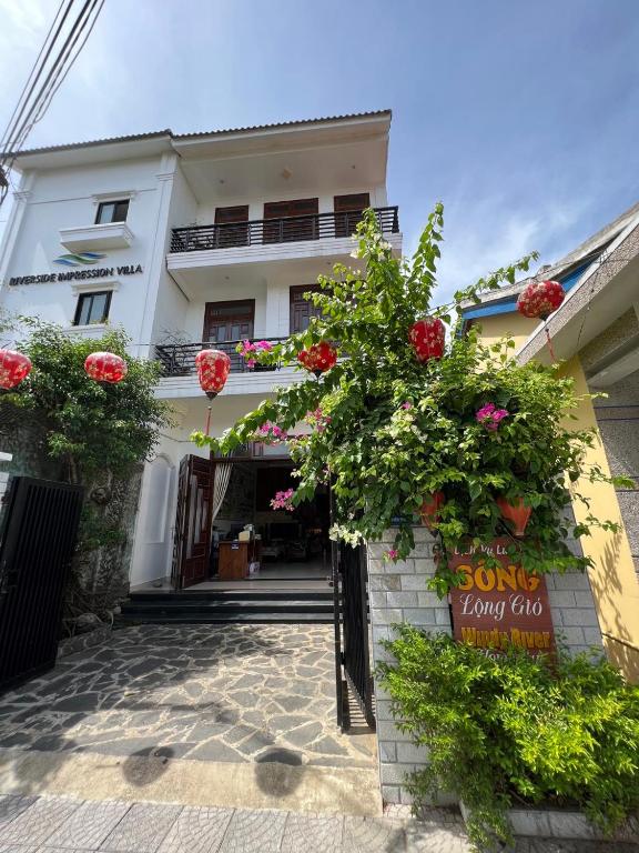 a white building with flowers in front of it at Windy River Homestay in Hoi An