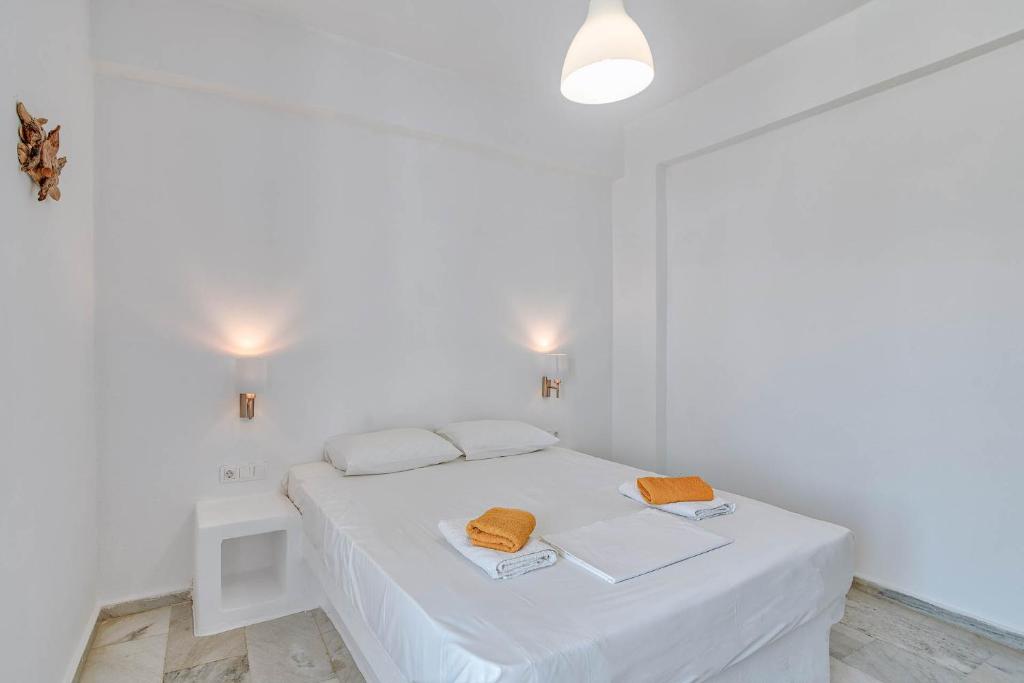 a white bedroom with a bed with two towels on it at Hotel Antiparos in Antiparos Town