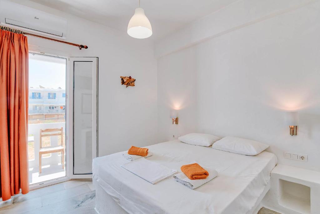 a white bedroom with a bed and a large window at Hotel Antiparos in Antiparos Town